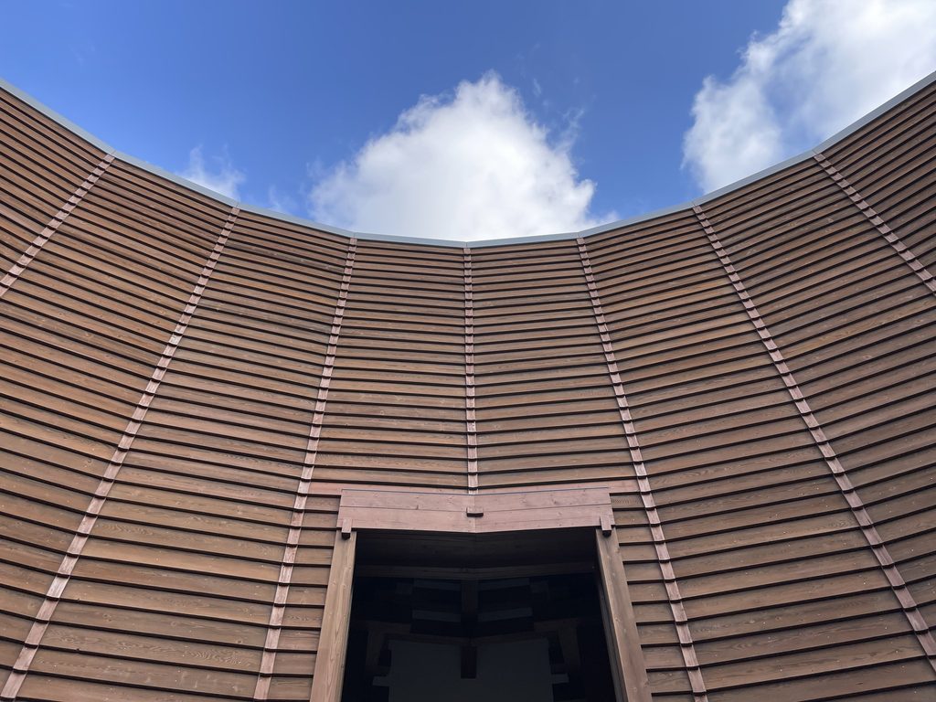 円形外壁の木製ルーバーと青空 / Curved timber louvers of the Museum of Wood against the sky
