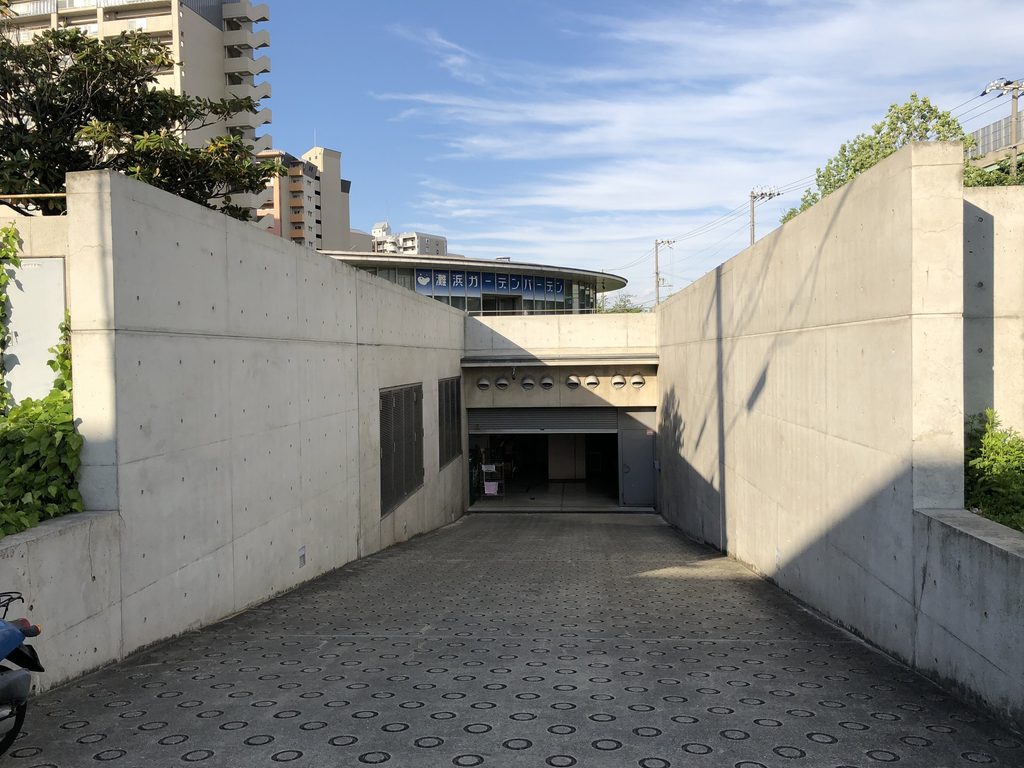 二枚の打放しコンクリート壁の間を半地下へ下る通路 / Passage descending between exposed-concrete walls toward the semi-subterranean level