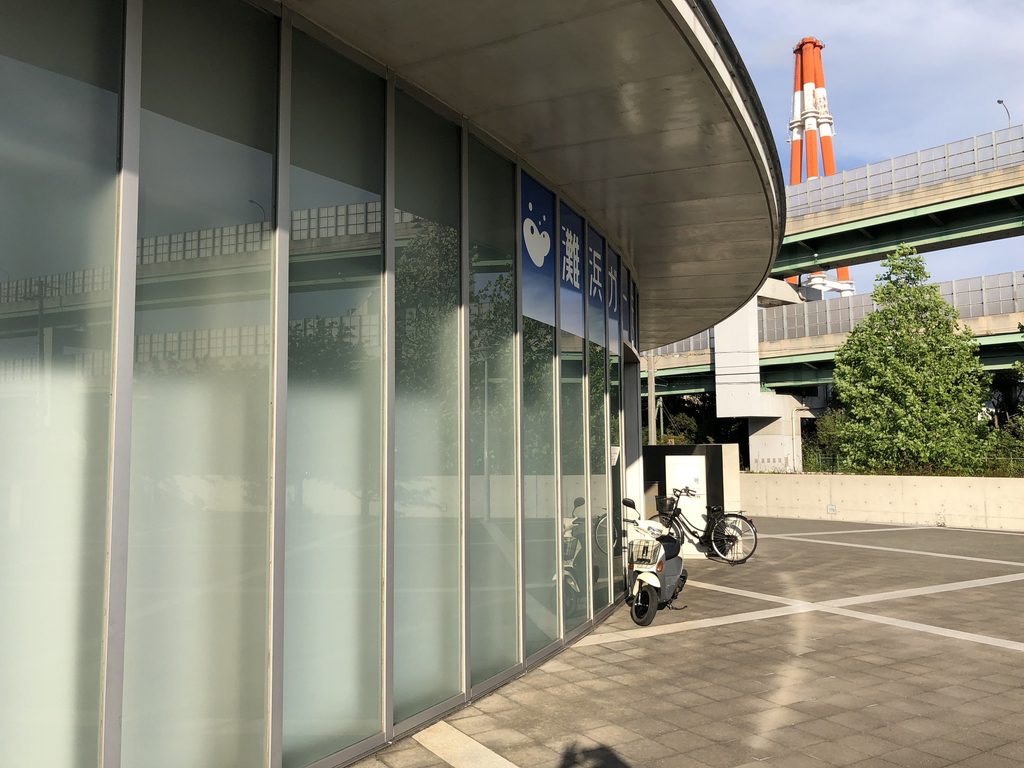 大きく張り出す庇に沿って湾曲する灘浜ガーデンバーデンのガラス外壁 / Curved glazed exterior of Nadahama Garden Baden beneath a projecting roof