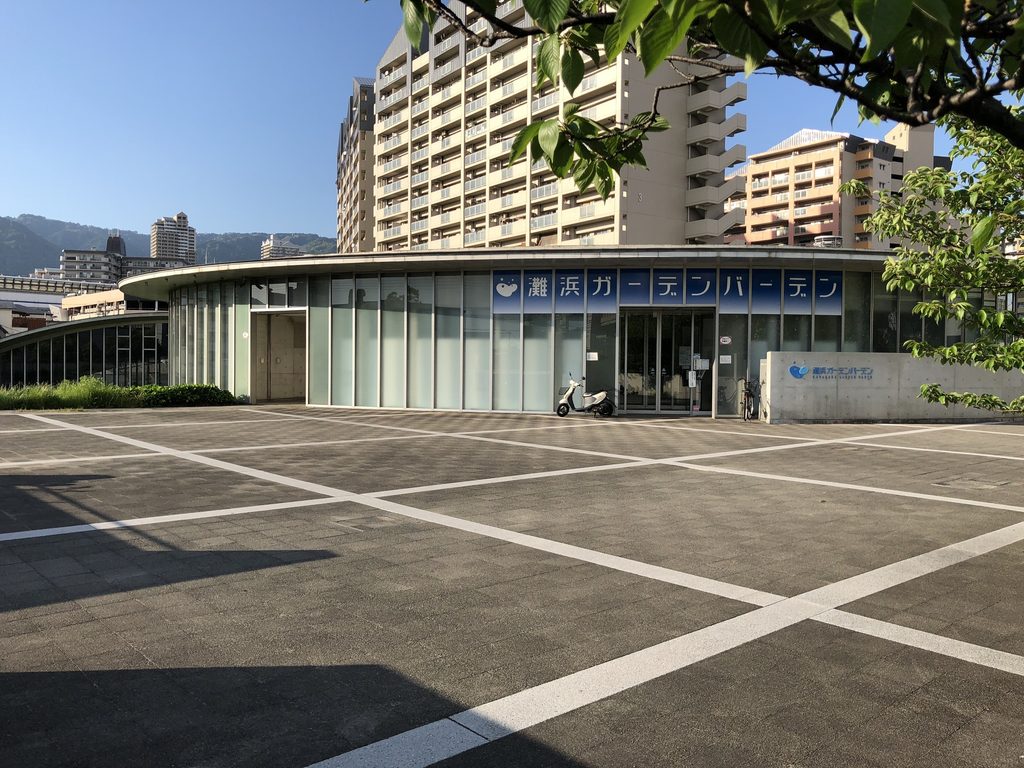 広場側から見る灘浜ガーデンバーデンの曲面ガラスファサードと入口 / Curved glazed facade and entrance of Nadahama Garden Baden viewed from the plaza