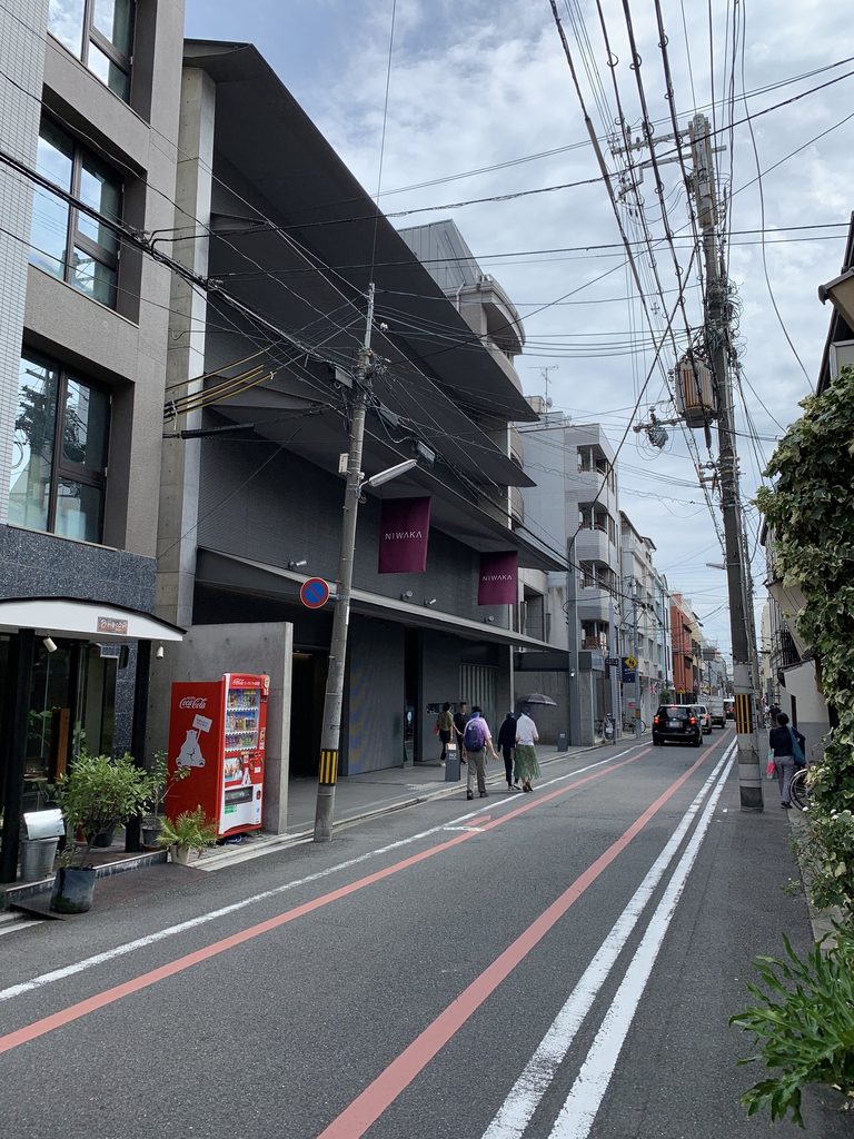 電線や周辺店舗とともに通りから見る俄ビル / NIWAKA Building seen from the street among overhead wires and neighboring shops