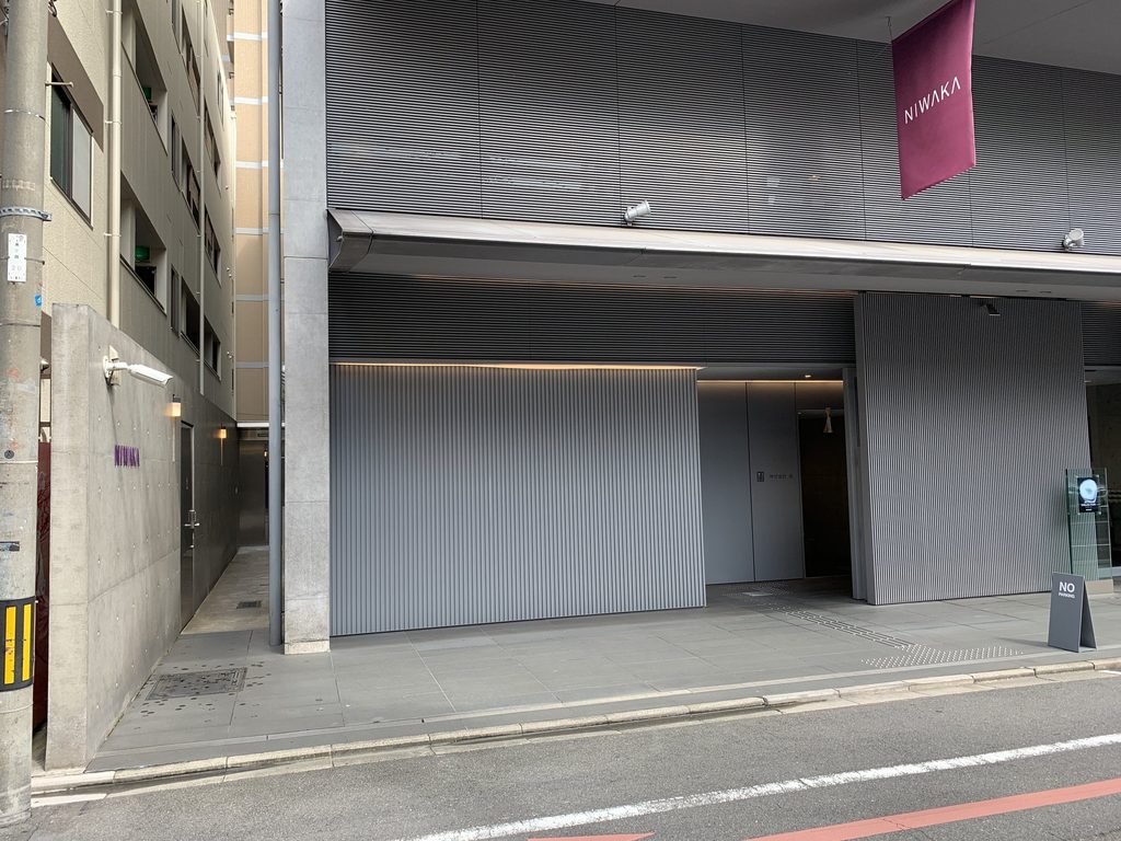 建物側面に続く打放しコンクリート壁と縦格子 / Exposed-concrete wall and vertical screen along the side of the NIWAKA Building