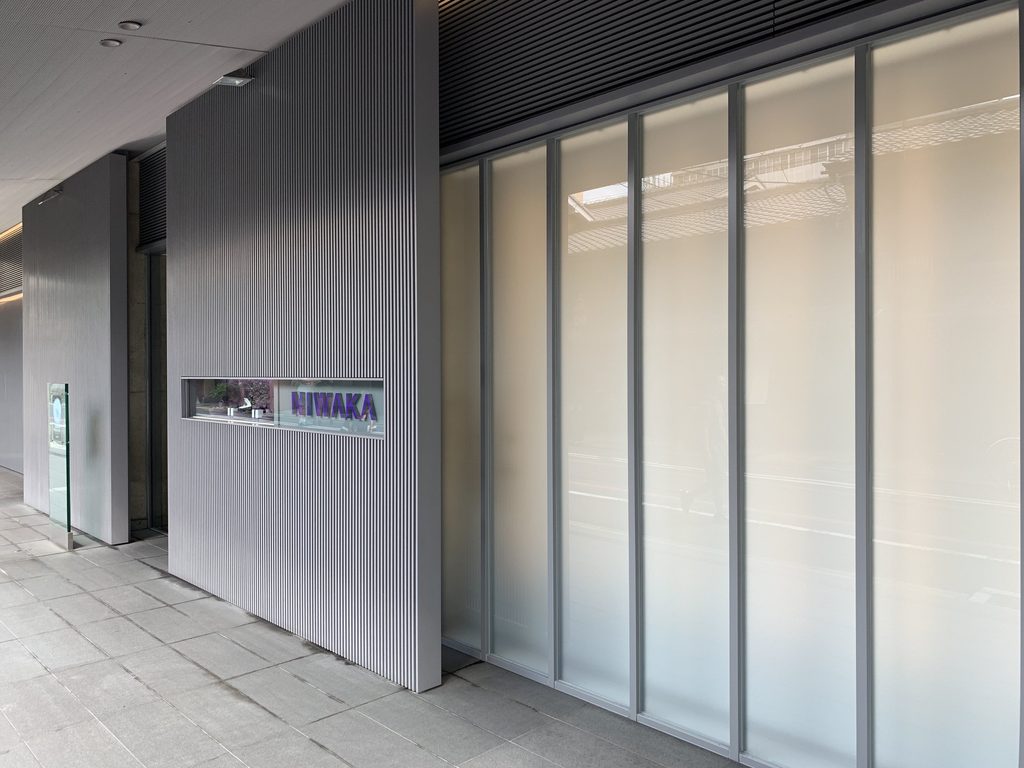 すりガラスと細長いNIWAKAサインを持つ街路側外壁 / Street facade with frosted glass and a narrow NIWAKA sign opening