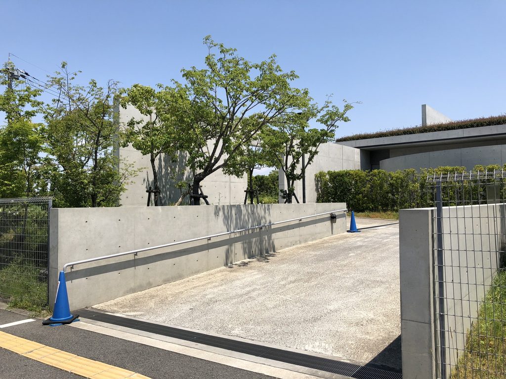 樹木と低いコンクリート壁に囲まれた老木レディスクリニック2の入口側 / Entrance approach of Oiki Ladies Clinic 2 framed by trees and low concrete walls