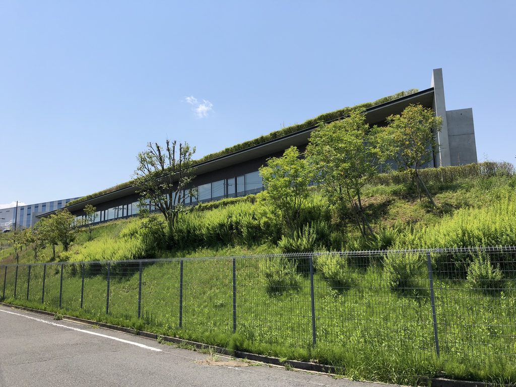 緑の斜面の上を長い水平屋根が伸びる老木レディスクリニック2 / Long horizontal roof of Oiki Ladies Clinic 2 extending above the green slope