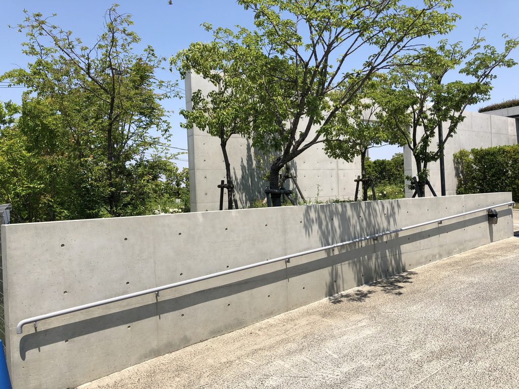 コンクリート壁と植栽に沿って奥へ続く老木レディスクリニック2のアプローチ / Approach to Oiki Ladies Clinic 2 continuing between concrete walls and planting