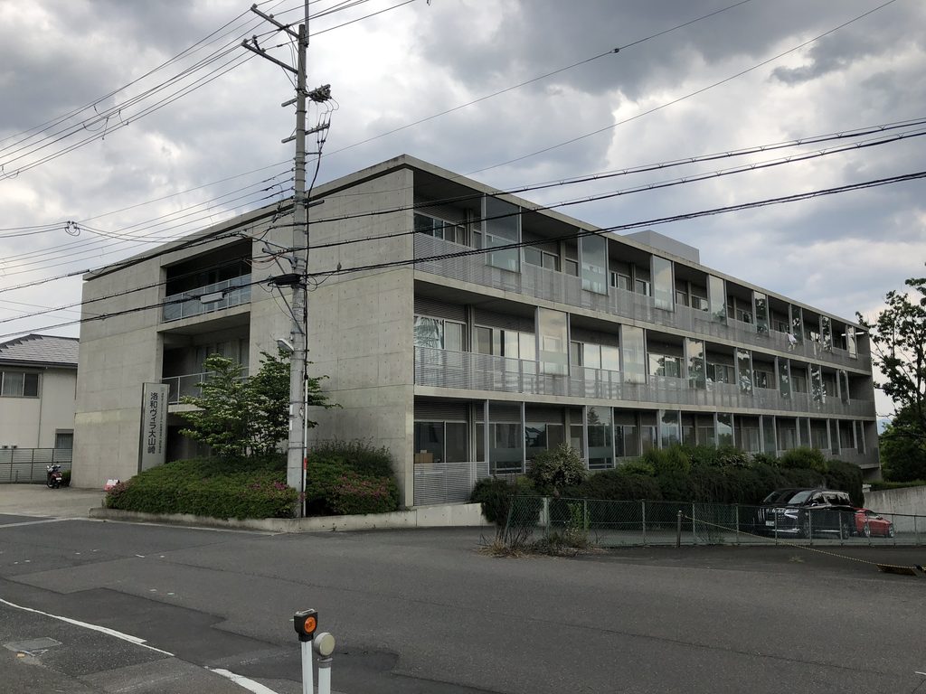 道路越しに見る洛和ヴィラ大山崎の長いコンクリート外観 / Long concrete exterior of Rakuwa Villa Oyamazaki seen from across the street
