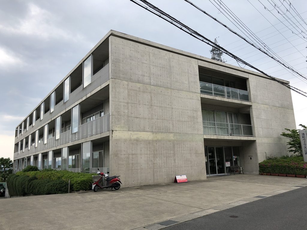 コンクリートの妻壁から長辺方向を見る洛和ヴィラ大山崎 / Rakuwa Villa Oyamazaki seen along its long elevation from the concrete end wall