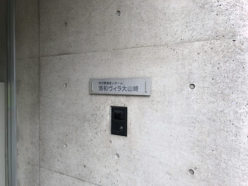 打放しコンクリート壁に掲げられた洛和ヴィラ大山崎の名称表示 / Rakuwa Villa Oyamazaki signage on an exposed-concrete wall