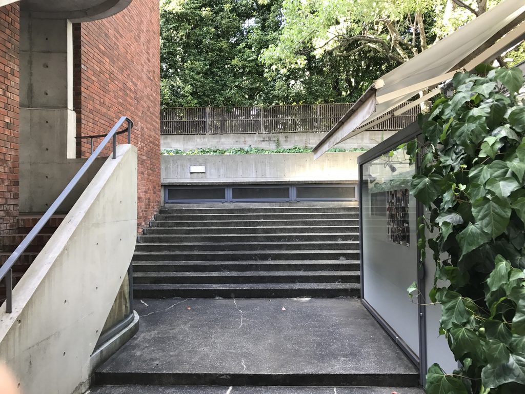 レンガ壁の間を進むRIN'S GALLERYの細い階段と通路 / Narrow stair and passage between brick walls at Rin's Gallery