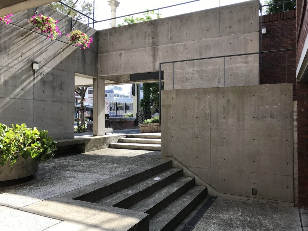 レンガ壁の脇に曲面コンクリートが現れるRIN'S GALLERYの外部空間 / Exterior space where curved concrete emerges beside brick at Rin's Gallery