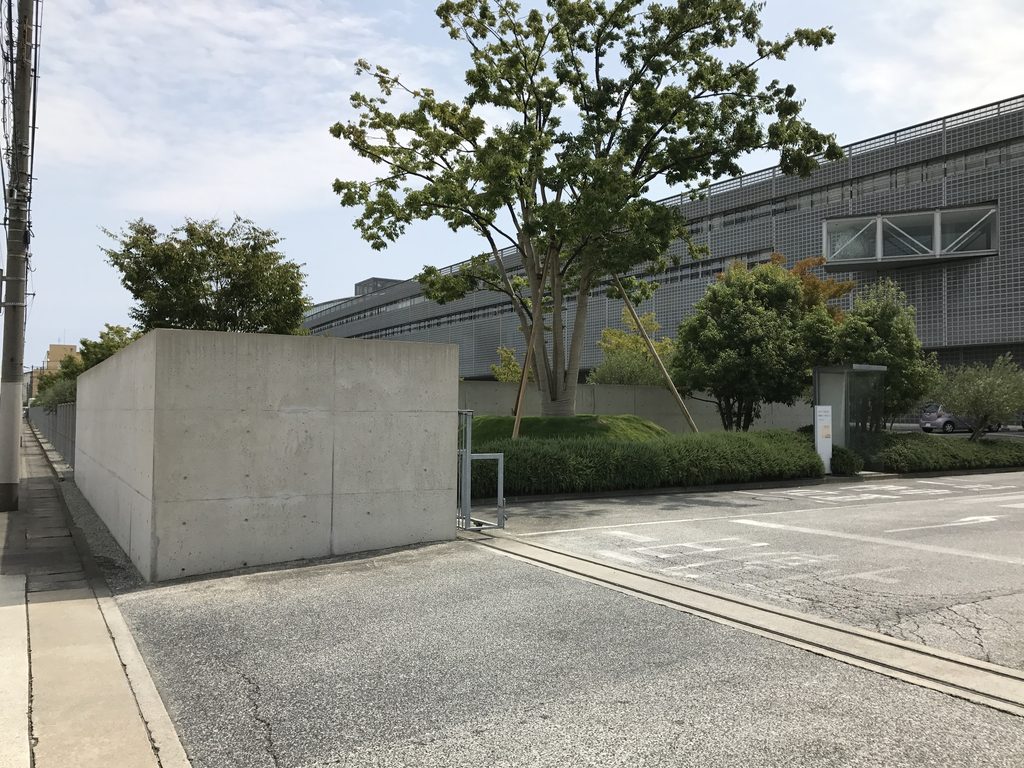 ロック・フィールド神戸ファクトリー入口付近の打放しコンクリート壁と工場棟 / Exposed-concrete wall and factory building near the entrance to ROCK FIELD Kobe Factory