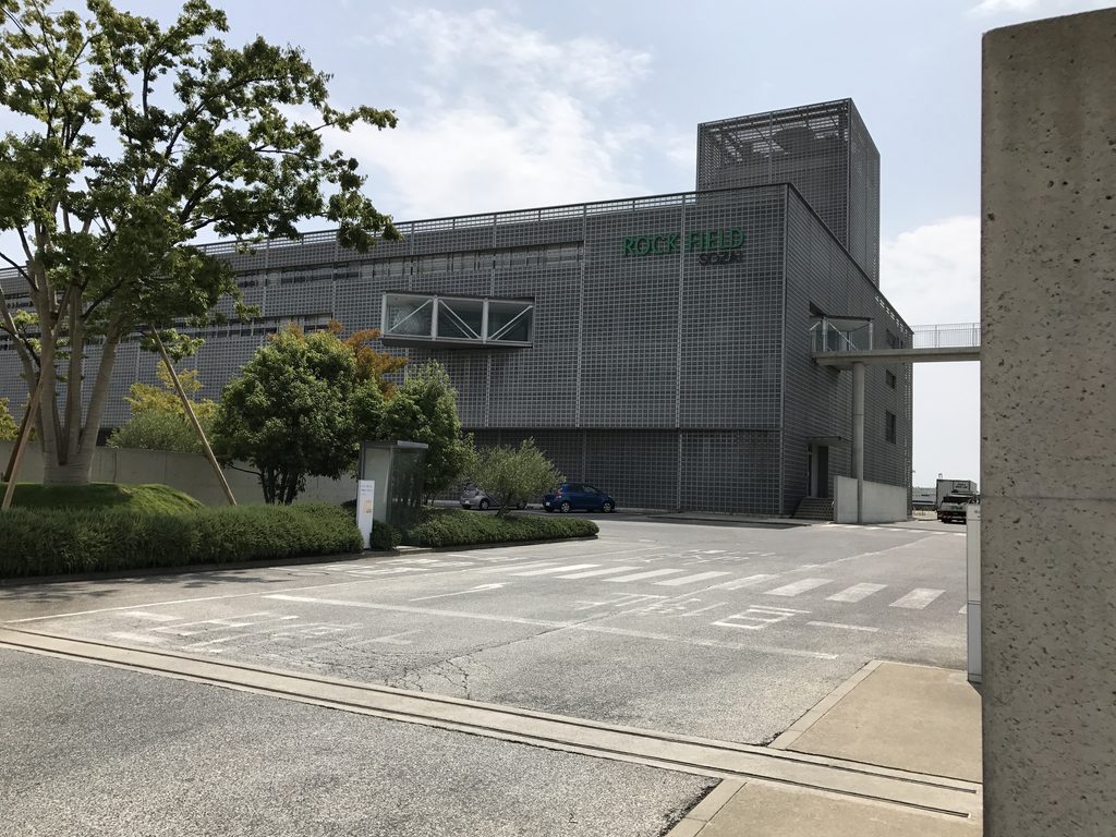 ロック・フィールド神戸ファクトリーの大きな工場棟と前面の植栽 / Large factory structure and foreground planting at ROCK FIELD Kobe Factory