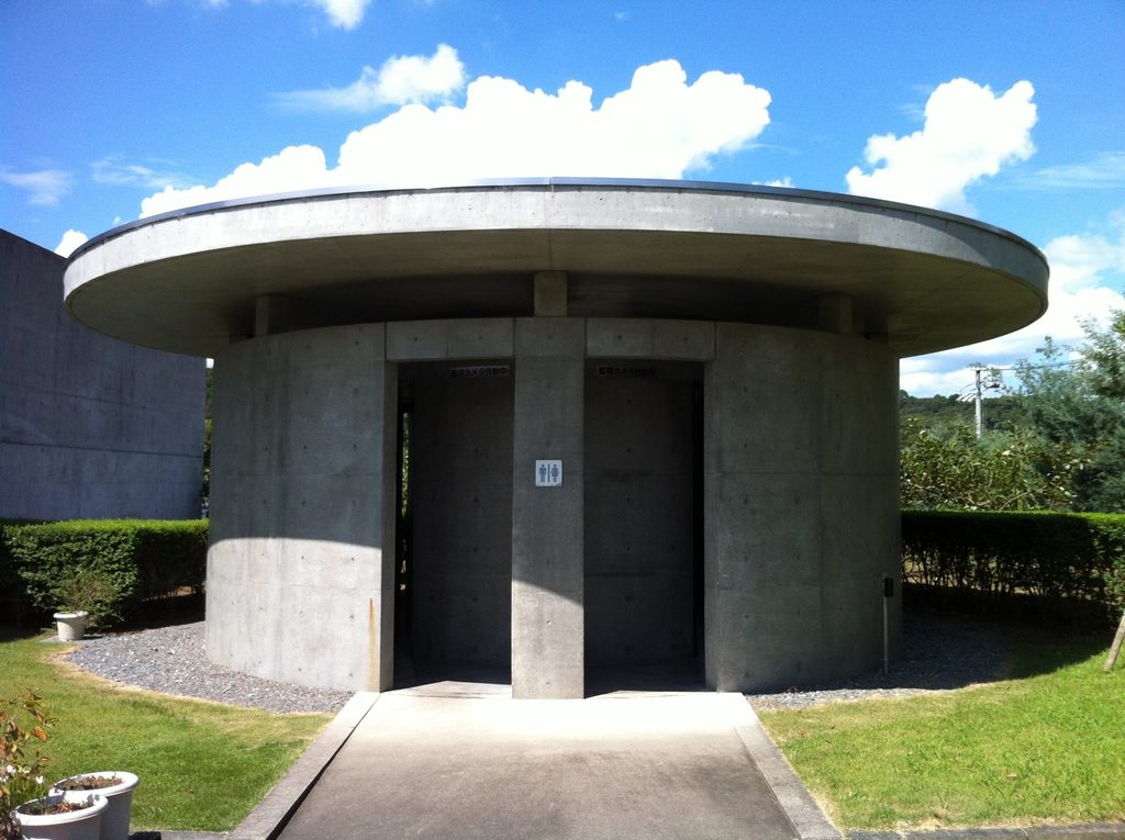 円形の庇とコンクリート壁が特徴的なロック・フィールド静岡ファクトリーのトイレ / Restroom building at Rock Field Shizuoka Factory characterized by its circular canopy and concrete walls