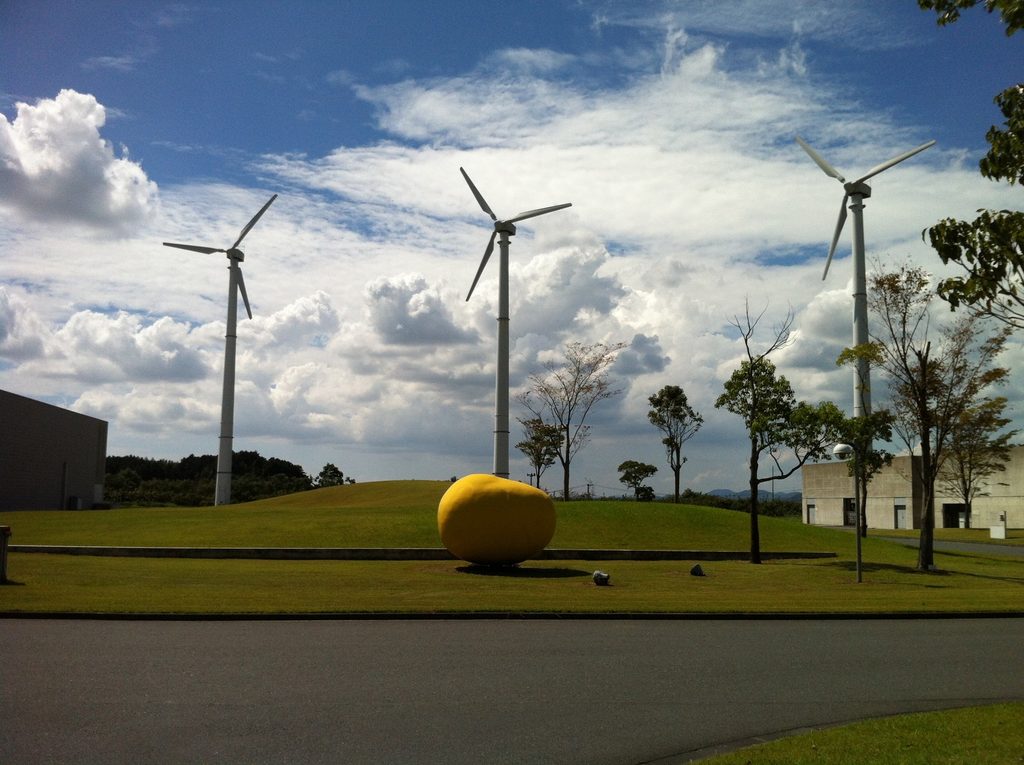 芝生に立つ風力発電設備と黄色い球体 / Wind turbines and yellow spherical object within the landscaped factory grounds