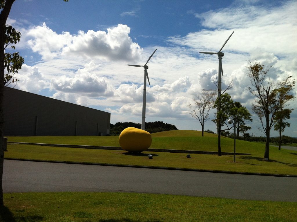 風車と黄色い球体を前景にした静岡ファクトリーのランドスケープ / Landscaped grounds of the Shizuoka Factory with wind turbines and yellow sphere