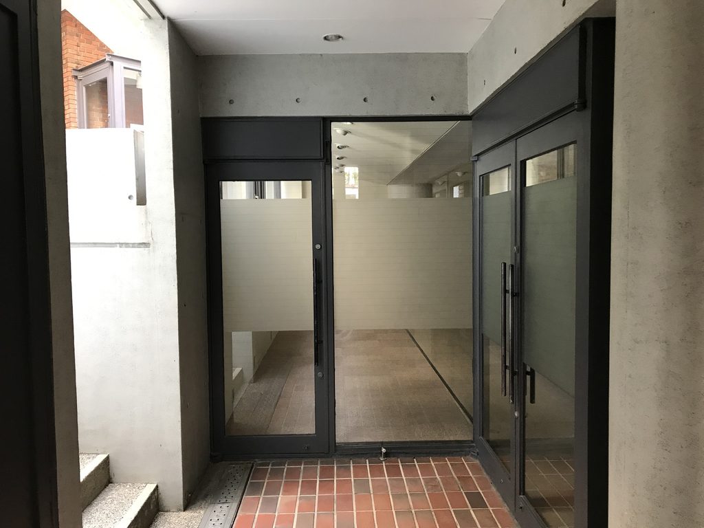 ローズガーデン内部で交差する打放しコンクリート壁と半屋外通路 / Exposed-concrete walls and semi-outdoor passages intersecting within Rose Garden