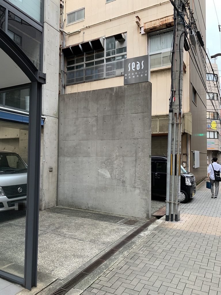 SEASのサインが掲げられた打放しコンクリートの側壁 / Exposed-concrete side wall of SEAS Building with the SEAS sign
