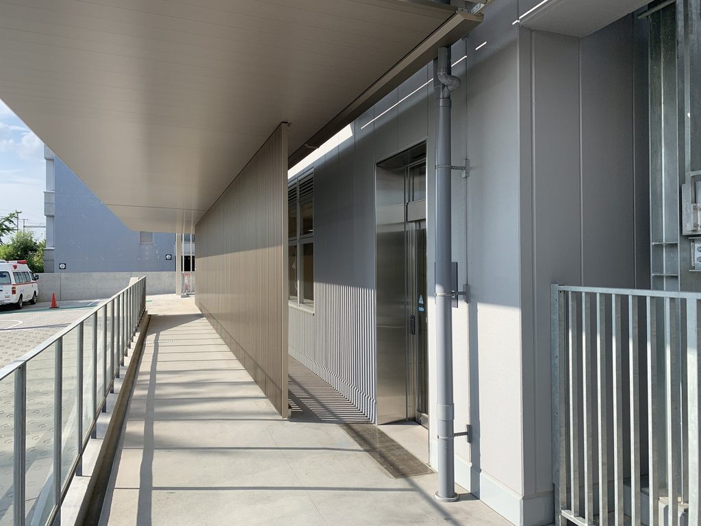 長い庇の下に続く堺平成病院の外部通路 / Exterior passage extending beneath a long canopy at Sakai Heisei Hospital