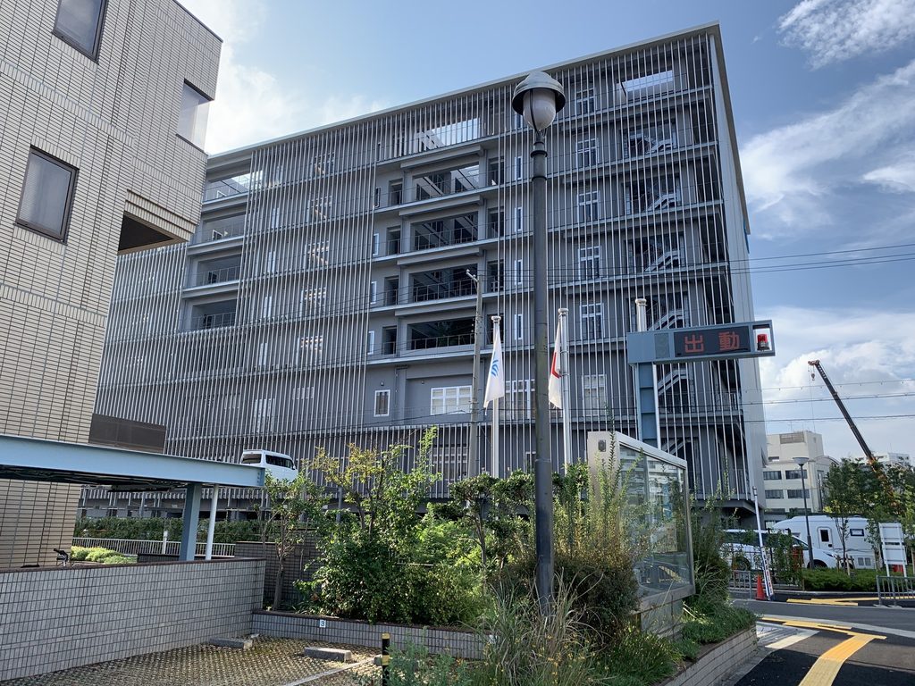 植栽越しに見る堺平成病院のルーバー外観 / Louvered exterior of Sakai Heisei Hospital seen beyond planting