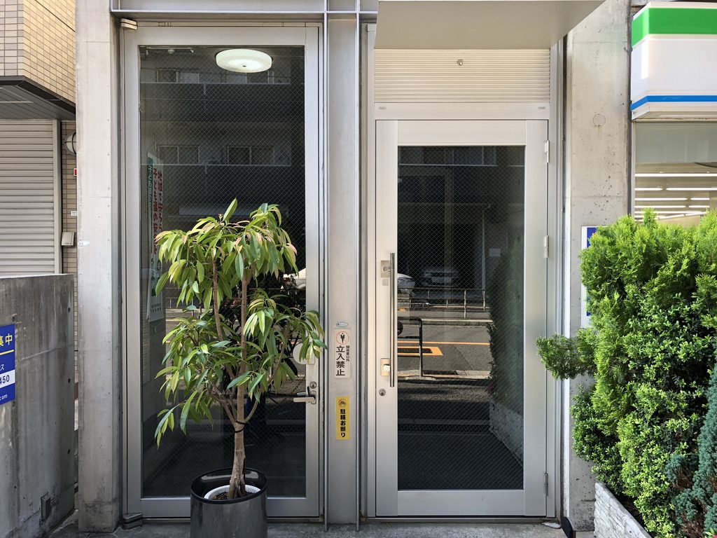 金属枠のガラス扉が並ぶサン・オークスビルの入口 / San Oaks Building entrance with metal-framed glass doors