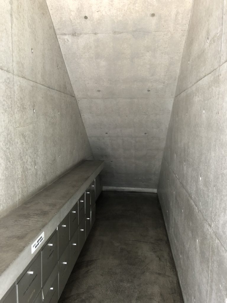 郵便受けと斜めに上がるコンクリート面のある共用通路 / Common passage with mailboxes and an inclined concrete plane above