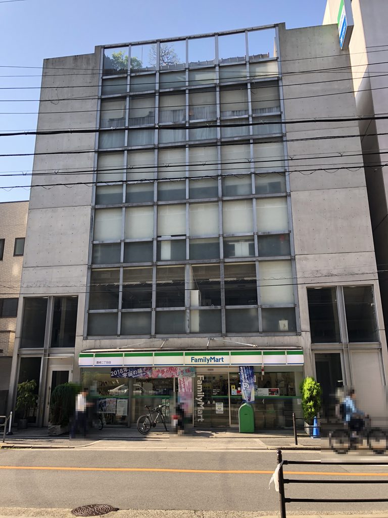 通りに面した大きなガラスの格子と打放しコンクリートの壁 / Large street-facing glass grid framed by exposed-concrete walls