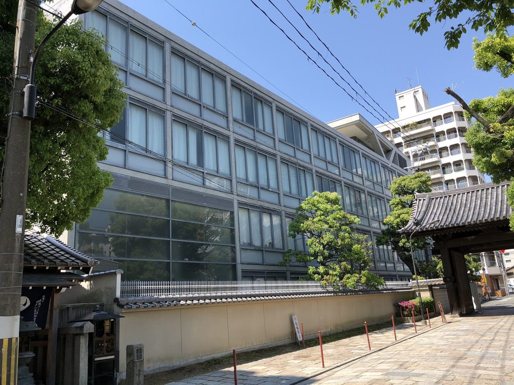 四天王寺の塀越しに見た四天王寺高等学校のガラス張りの立面 / Glazed elevation of Shitennoji High School seen beyond the wall of Shitennoji Temple