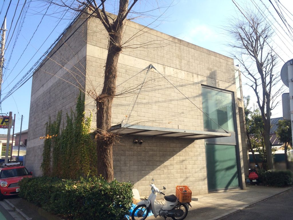 ブロック壁と蔦が重なる旧SUPER POTATO本社の外観 / Concrete-block wall and ivy at the former SUPER POTATO headquarters