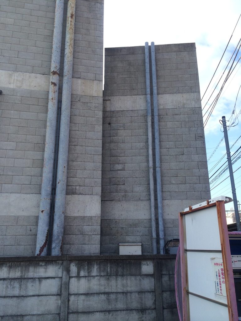 水平に積まれたブロックと縦の部材が並ぶ旧SUPER POTATO本社の壁面 / Wall of the former SUPER POTATO headquarters with horizontal block courses and vertical elements