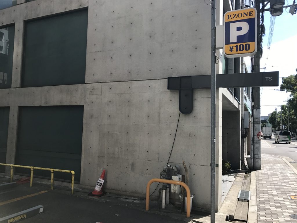 TSビル側面の打放しコンクリート壁と突出したTSサイン / Exposed-concrete side wall and projecting TS sign of TS Building
