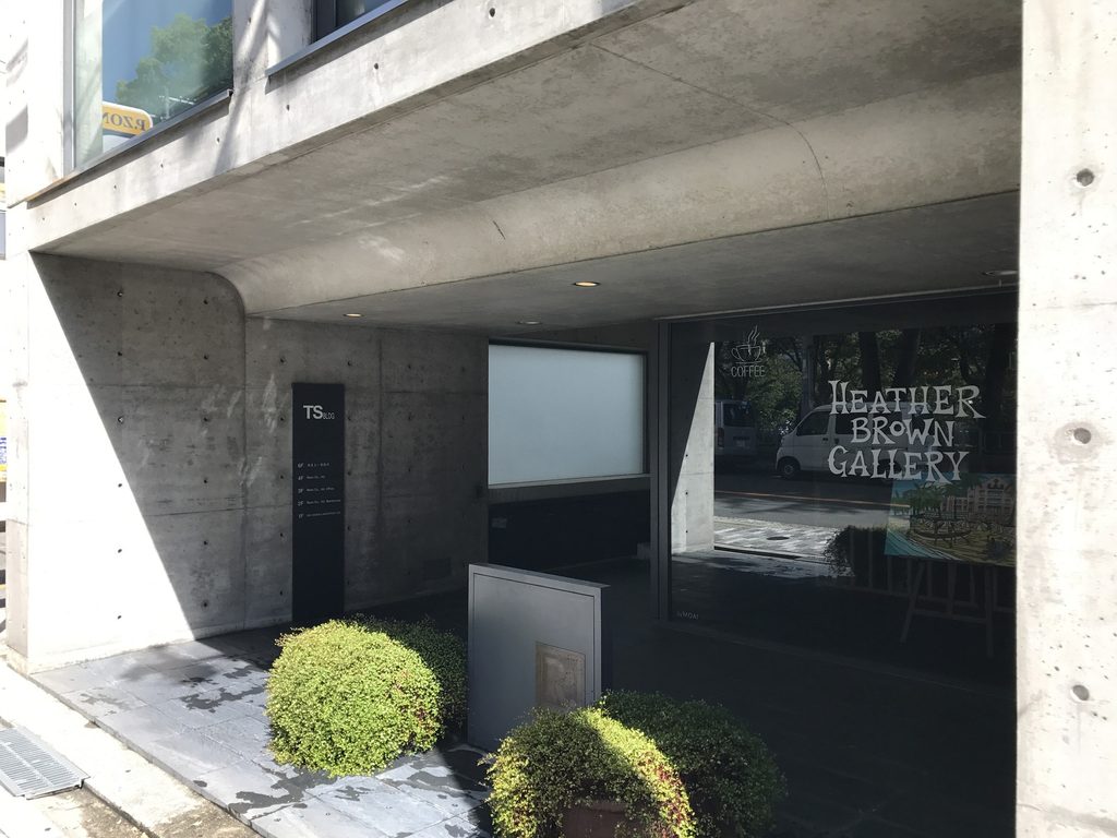 打放しコンクリートの庇の下に設けられたTSビルの入口と店舗ガラス面 / Entrance and glazed storefront beneath the exposed-concrete canopy of TS Building