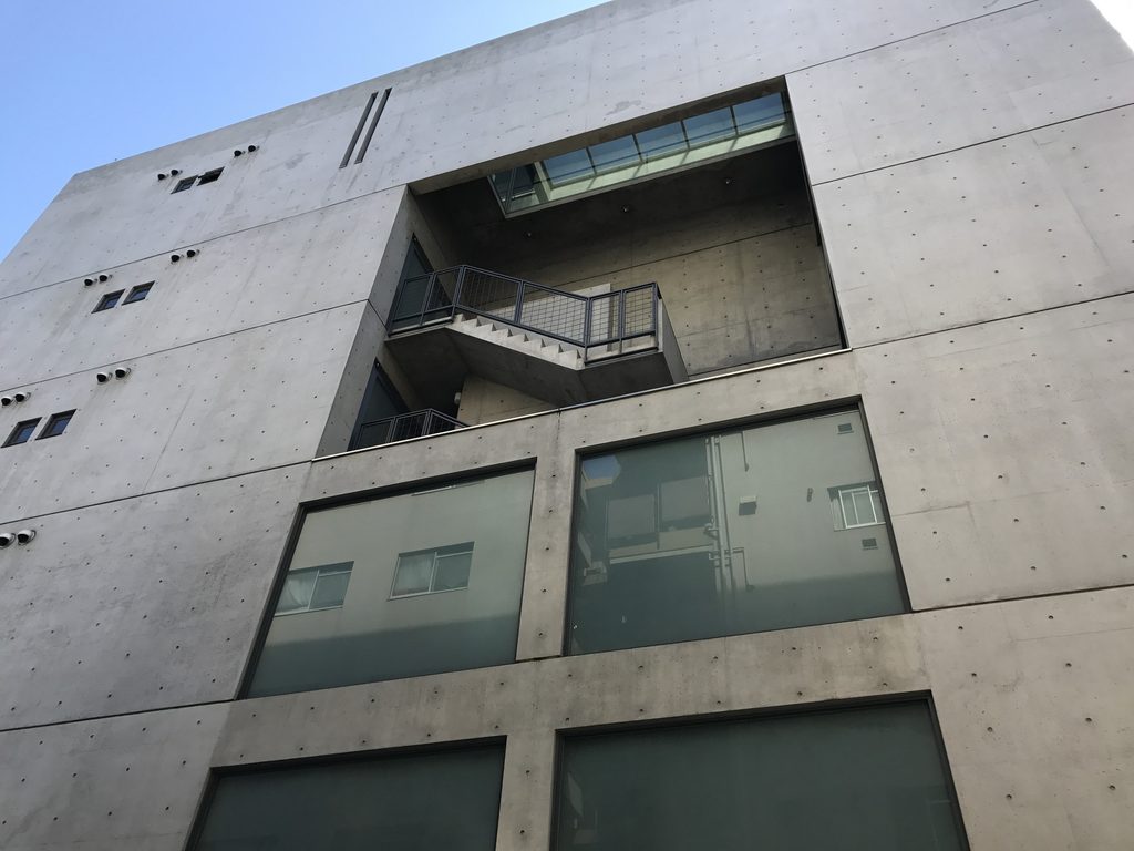 TSビル側面上部に開かれた吹き抜けと外部階段状の構成 / Upper void and stair composition visible on the side of TS Building