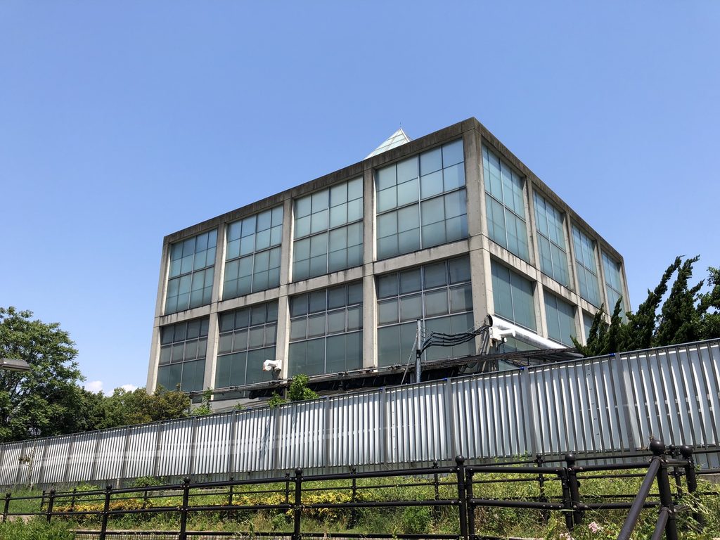 公園外周から見る天王寺博覧会テーマ館のガラス張り矩形棟 / Glazed rectangular volume of the Main Pavilion for the Tennoji Fair seen from the park perimeter
