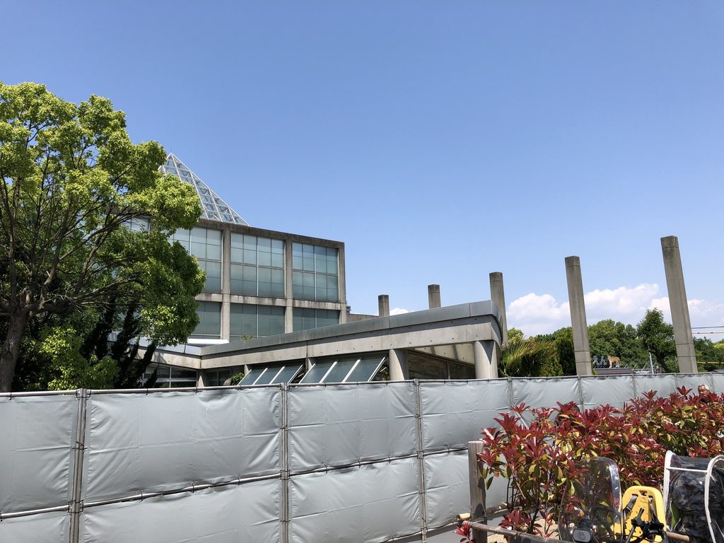 三角形のガラス屋根と柱列を斜めから見る天王寺博覧会テーマ館 / Oblique view of the pyramidal glass roof and columns of the Main Pavilion for the Tennoji Fair