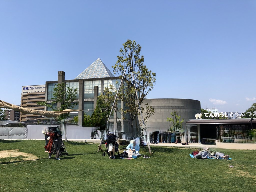 芝生と樹木越しに見る天王寺博覧会テーマ館の最晩年の外観 / Final-years exterior of the Main Pavilion for the Tennoji Fair seen across lawn and trees
