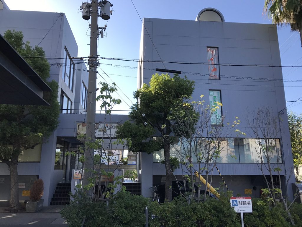 樹木越しに見る帝塚山タワープラザの道路側ファサード / Street facade of Tezukayama Tower Plaza seen through trees