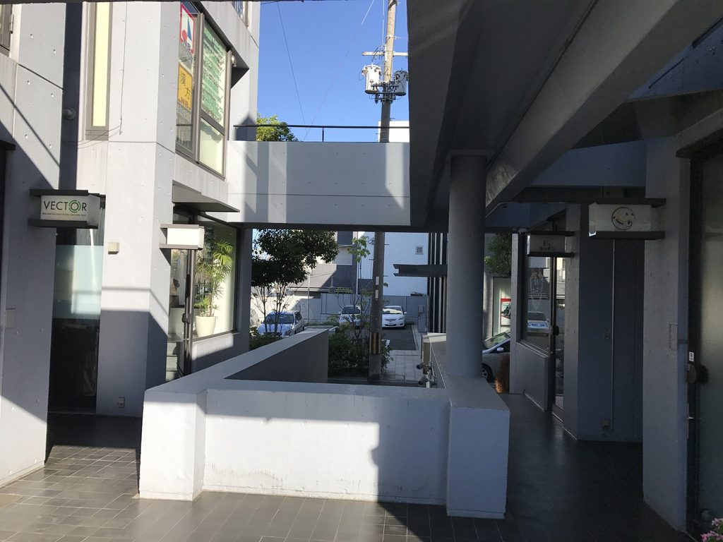 コンクリートの壁と梁に囲まれた帝塚山タワープラザの外部通路 / Exterior passage enclosed by concrete walls and beams at Tezukayama Tower Plaza