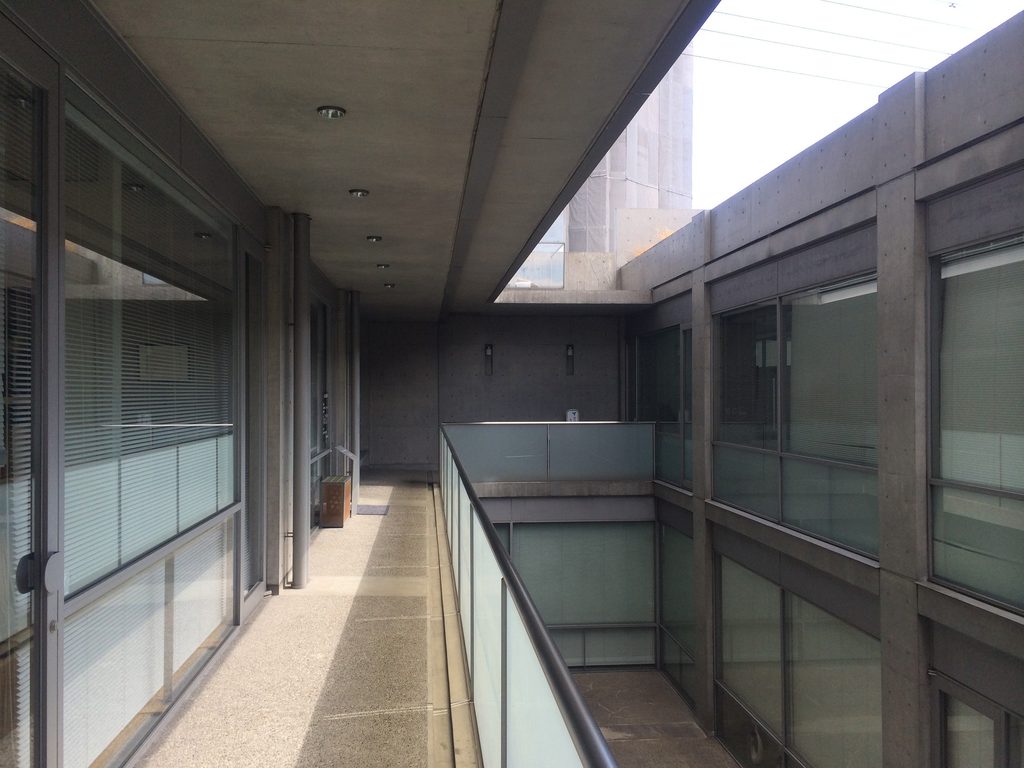 乳白色のガラス手摺に沿って延びるTHE QOLの上階回廊 / Upper-level walkway at THE QOL with translucent glass balustrades