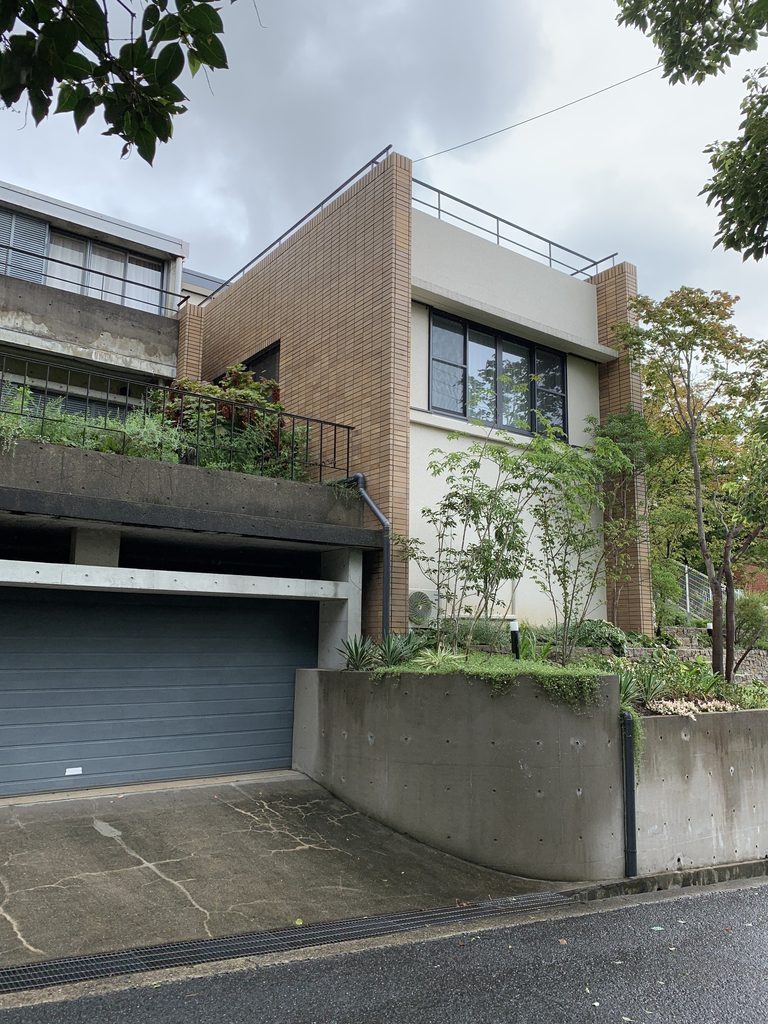 タイル壁と白い壁面、植栽が並ぶビューコート朝日ケ丘の外観 / Exterior of Viewcourt Asahigaoka with tiled walls, white surfaces and vegetation