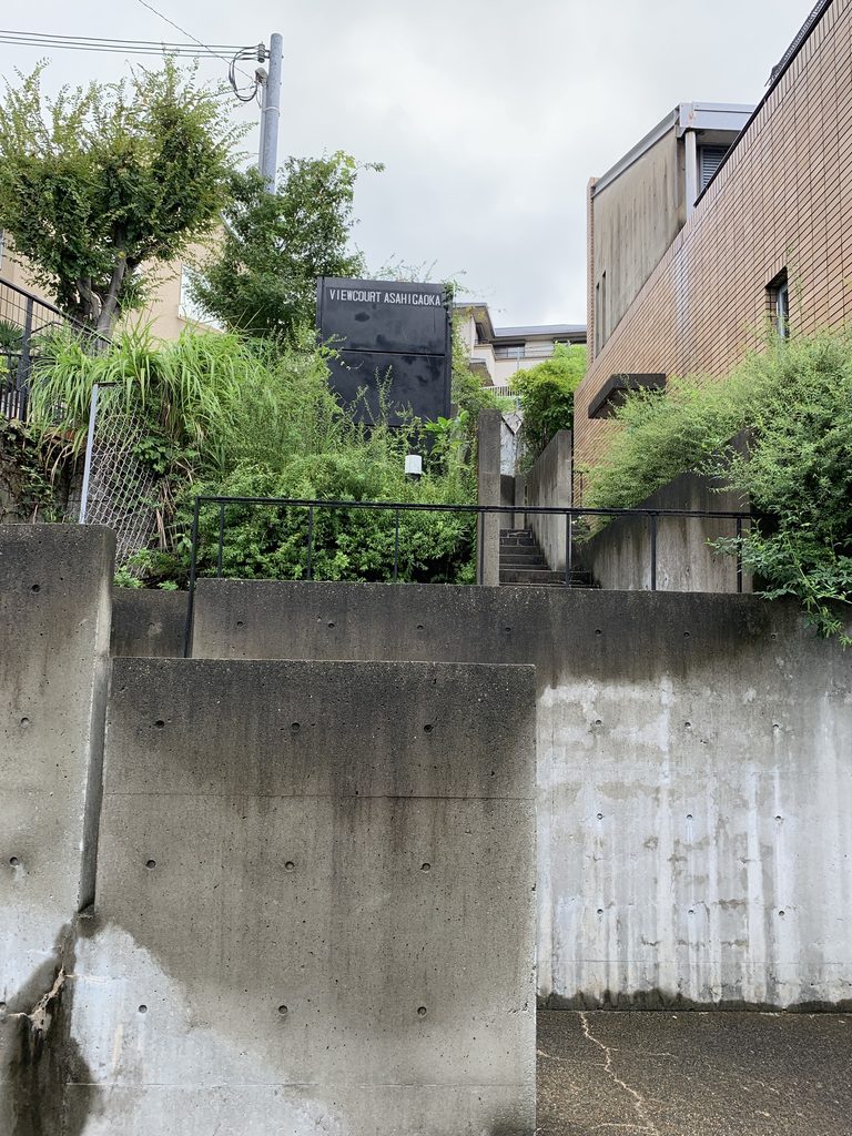 VIEWCOURT ASAHIGAOKAのサインと敷地内へ続く階段 / VIEWCOURT ASAHIGAOKA sign and stairway leading into the property
