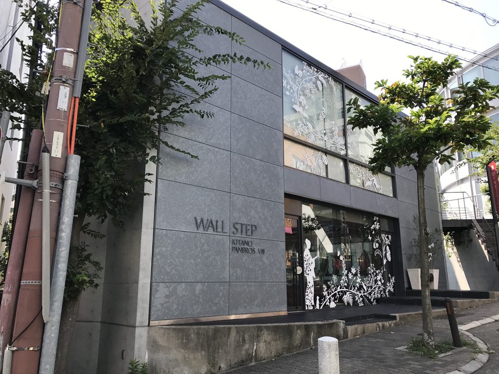 神戸・北野の街路から見たWALL STEPのガラスと暗色外装の正面 / Street facade of WALL STEP in Kobe’s Kitano district with glazing and dark exterior panels
